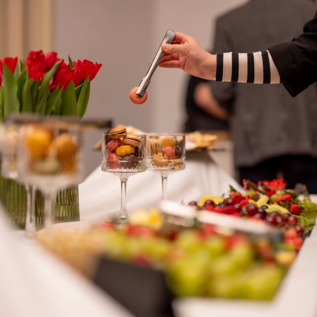 Osoba poslužuje zalogaje na catering stolu
